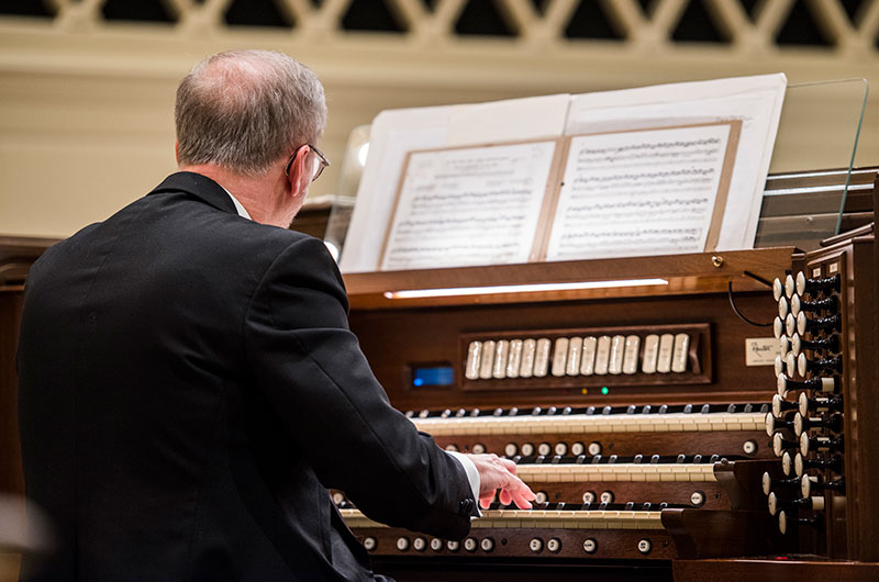 An organist playing the organ in Snidow Chapel