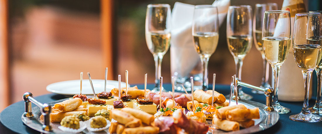 A platter of appetizers next to several glasses with champagne