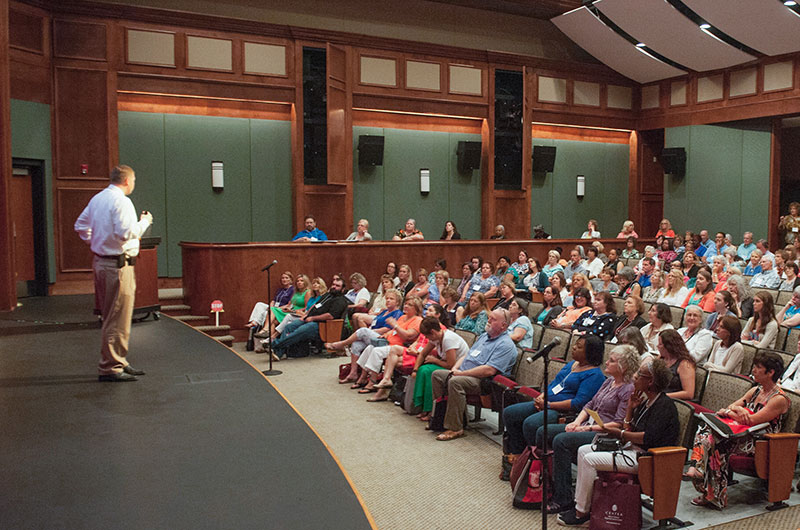 A presenter in Sydnor Performance Hall with a full audience