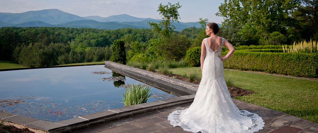 A bride is standing near the Virginia Claytor Memorial Gardens reflecting pool